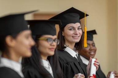 Lächelnde Absolventin mit Diplom im Vordergrund, umgeben von Kommilitoninnen – Ausdruck von Frauenbildung und Gleichstellung der Geschlechter.