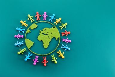 "Menschen aus aller Welt auf einem Globus, symbolisieren die globale Wirkung von Spenden von Unternehmen für die Gesellschaft."